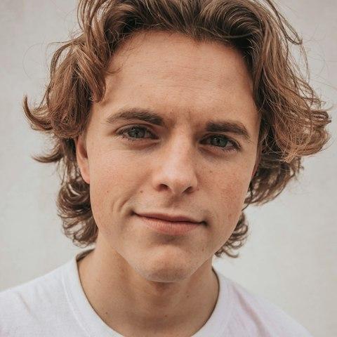 Young man with wavy hair and a soft smile